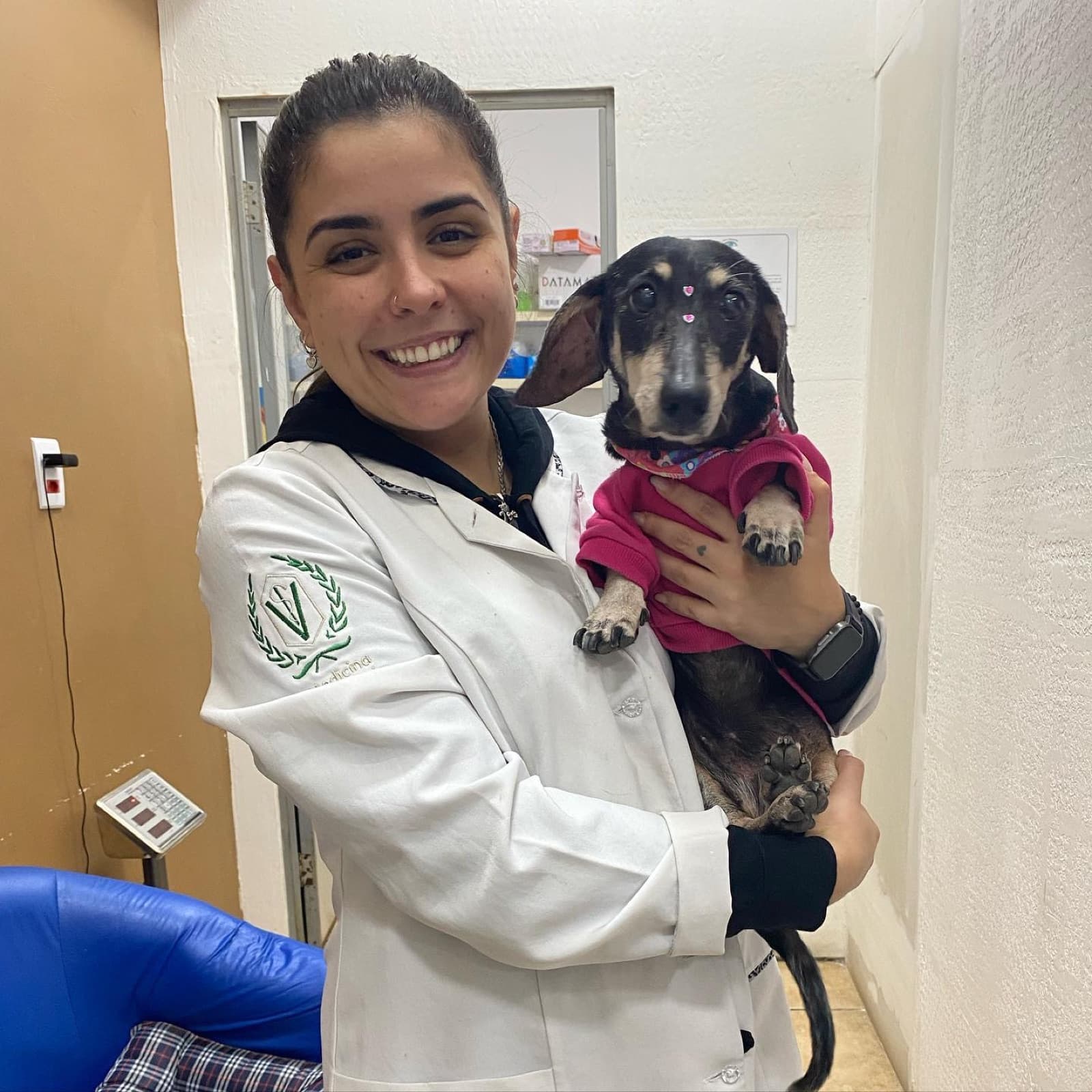 Dra. Danielle Rodrigues segurando um cão dachshund no colo durante um atendimento